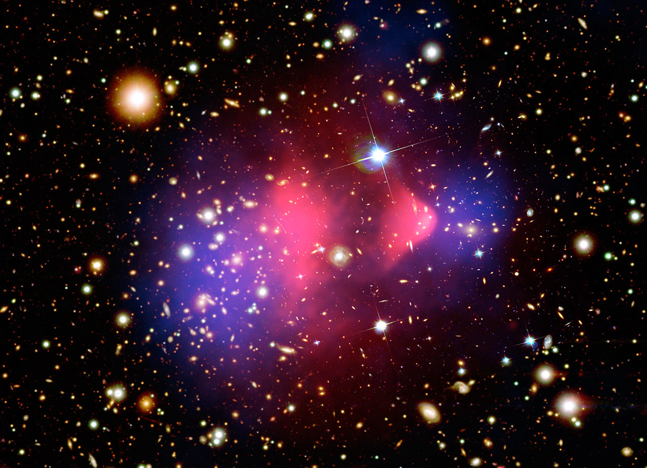 Bullet Cluster: blå linsningsberäknade massområden ligger förskjutna från rosa röntgenlysande gasmoln, mot en bakgrund av galaxer.